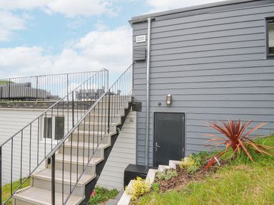 Exterior view of a building with stairs leading to a rooftop terrace and a garden with plants at 100 Hillside Villas in Looe