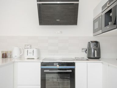 A kitchen with a stovetop oven toaster kettle air fryer and built in microwave at 100 Hillside Villas in Looe