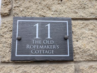 A stone plaque with the number 11 and text The Old Ropemakers Cottage on a stone wall at Old Ropemakers Cottage in Bridport