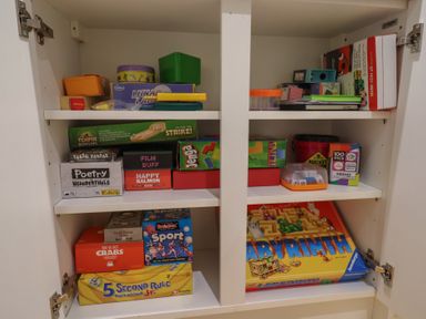 A cupboard filled with board games and card games on shelves at Old Ropemakers Cottage in Bridport