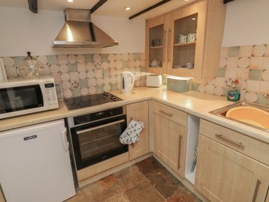 A kitchen with microwave oven stove and sink with cupboards at Fishnets in Brixham