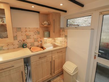 A kitchen with a sink cabinet countertop window and a trash bin at Fishnets in Brixham
