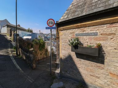 A narrow street with a stone wall and a sign reading Fisherman's Church and a no cycling sign at Fishnets in Brixham