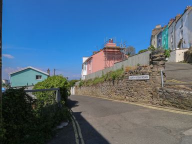 A street view with stone walls and colorful houses on North View Road in Brixham