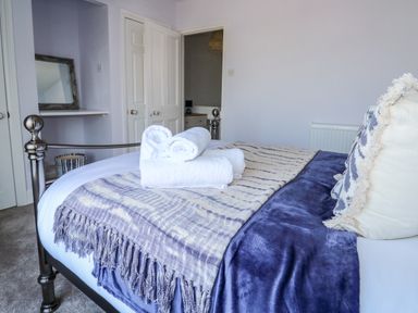 A bedroom with a metal bedframe pillows blankets and rolled towels at Fishnets in Brixham