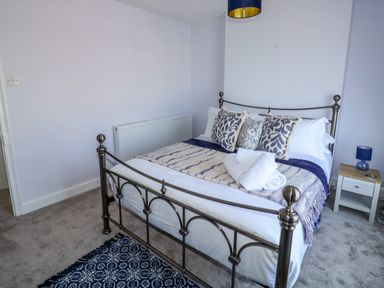 A bedroom with a metal bed frame pillows a small bedside table and a carpet at Fishnets in Brixham