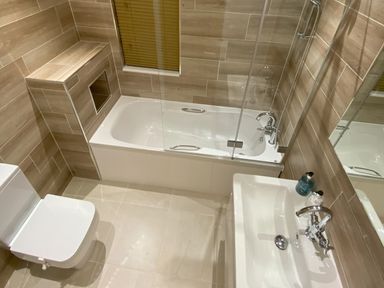 A bathroom with a bathtub a toilet a sink and a glass shower screen at Lodge 18 - The Pines in Runswick Bay