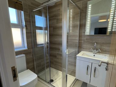 A bathroom with a glass shower enclosure a toilet and a sink with storage cabinet at Lodge 18 - The Pines in Runswick Bay