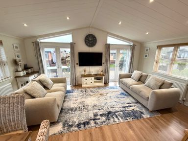 A living room with a television and large windows at Lodge 18 - The Pines Runswick Bay