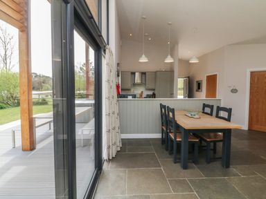 A dining area with wooden table and chairs adjacent to a kitchen with cabinets and pendant lights at Silver Birch in Dolton