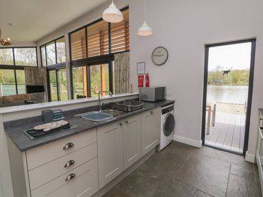 A kitchen with sink oven and washing machine with door open to lakeside at Silver Birch in Dolton