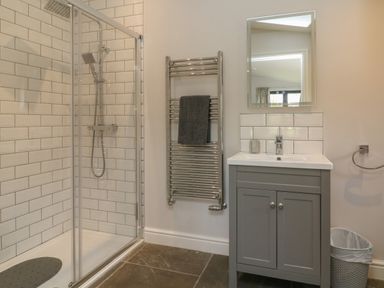 A bathroom with a shower enclosure a towel rack a sink cabinet with a mirror and a waste bin at Silver Birch in Dolton