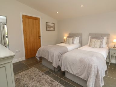 A bedroom with two single beds a wooden door and bedside tables with lamps at Silver Birch in Dolton