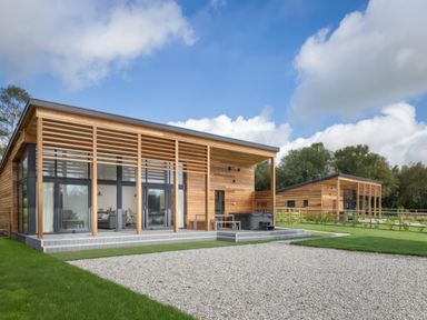 Two modern wooden houses with large glass windows and gravel area in front at Silver Birch in Dolton