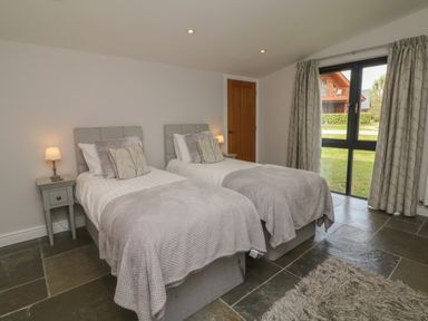 A bedroom with two single beds bedside tables lamps and a window with curtains at Cherry in Dolton