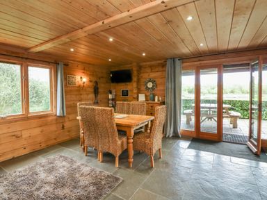 A dining area with wooden table and rattan chairs next to large glass doors overlooking a patio at Aspen Dolton