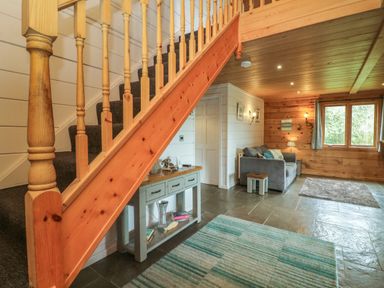 A staircase with wooden railing next to a gray sofa and a console table in a room with wooden walls at Aspen in Dolton