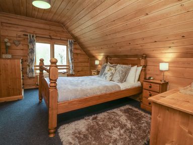 A bedroom with a wooden bed a dresser two bedside tables and a window at Aspen in Dolton