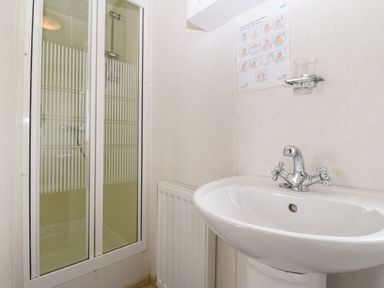 A bathroom with a shower enclosure and a sink with taps at Tir Glyn Caravan in Uwch Mynydd near Aberdaron