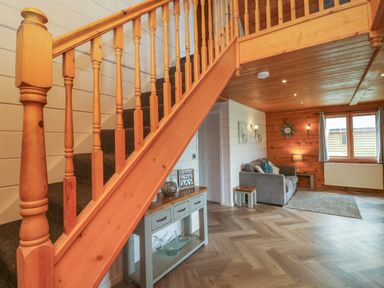 A living room with wooden staircase and gray sofa at Maple in Dolton