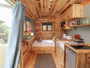 A small wooden interior with a bed at the end and a kitchenette on the right at Tower Hut in Ryde