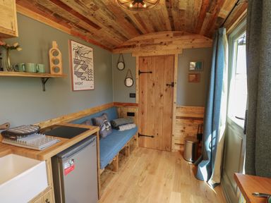 A small kitchen area with a blue sofa and wooden door at Tower Hut in Ryde