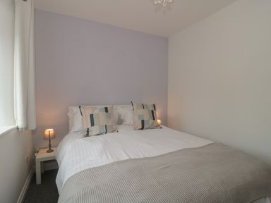 A bedroom with a double bed with patterned pillows and bedside tables with lamps at Primrose Cottage in Brendon Hill near Roadwater