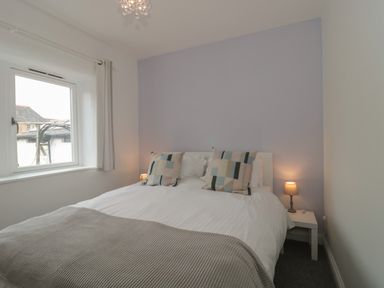 A bedroom with a double bed two bedside tables with lamps and a window at Primrose Cottage in Brendon Hill near Roadwater