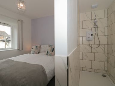A bedroom with a double bed next to a tiled shower area at Primrose Cottage Brendon Hill near Roadwater
