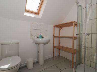 A bathroom with a toilet sink wooden shelving unit and a glass shower at Primrose Cottage in Brendon Hill near Roadwater