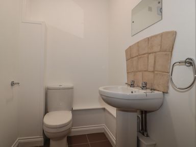 A small bathroom with a toilet and a pedestal sink with tiled backsplash at Primrose Cottage in Brendon Hill near Roadwater