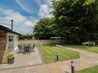 A garden with a patio area and outdoor dining table and chairs at Primrose Cottage in Brendon Hill near Roadwater