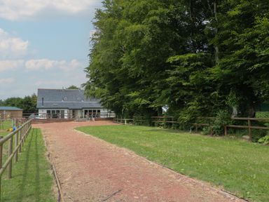 A pathway leading to a white house with a slate roof surrounded by grass and trees at Primrose Cottage in Brendon Hill near Roadwater