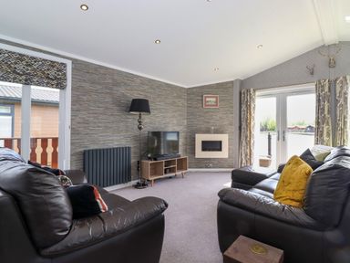 A living room with leather sofas a television and a fireplace at Capenwray in Carnforth