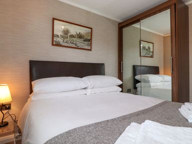 A bedroom with a bed a lamp a framed picture and a mirrored wardrobe at Capenwray in Carnforth
