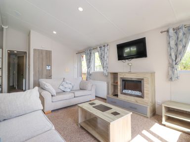 A living room with sofas a coffee table a wall mounted tv and fireplace at Coniston in Carnforth
