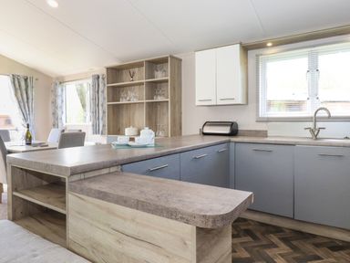 A kitchen with blue lower cabinets wooden countertops and open shelving with glassware at Coniston in Carnforth
