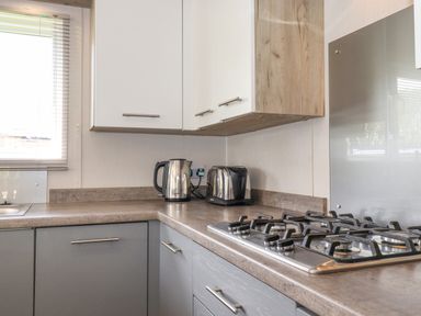 A kitchen corner with a gas stove kettle toaster and cabinets at Coniston in Carnforth