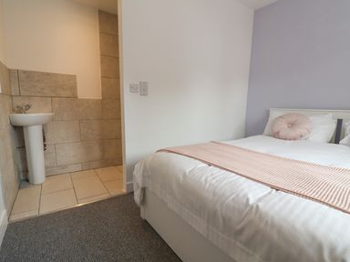 A bedroom with a bed and a small sink area with tiled walls at Campion Cottage in Brendon Hill near Roadwater