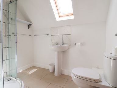 A bathroom with a shower, sink, toilet, skylight window and towel racks at Campion Cottage in Brendon Hill near Roadwater
