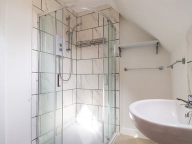 A bathroom with a glass shower enclosure and a white sink at Campion Cottage in Brendon Hill near Roadwater