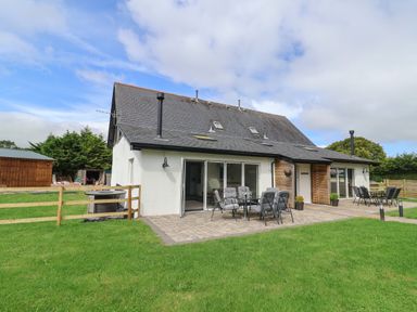 A house with a patio and outdoor furniture on a grass lawn at Campion Cottage in Brendon Hill near Roadwater