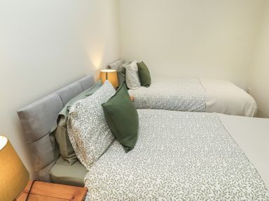 A bedroom with two beds and bedside lamps at Cragg Lodge in West Woodburn
