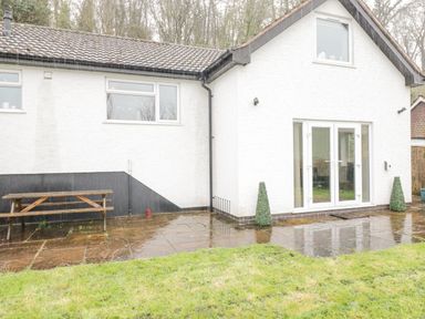 A white house with a tiled roof patio doors small grass area and a wooden picnic table at The Brambles in Monmouth