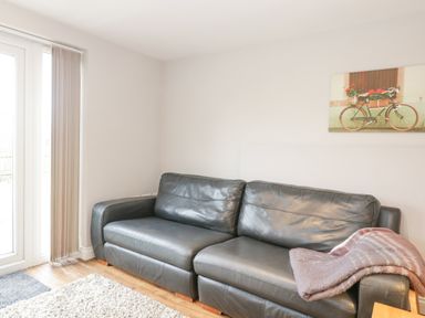 A black leather sofa with a blanket next to glass doors in a living room at The Brambles in Monmouth