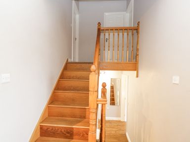 A staircase with wooden steps and railing leading to a landing with white doors at The Brambles in Monmouth