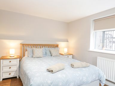 A bedroom with a double bed bedside tables with lamps and a window at The Brambles in Monmouth