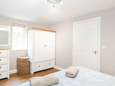 A bedroom with a bed with towels on it a white wardrobe and a wicker basket at The Brambles in Monmouth