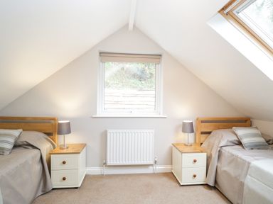 A bedroom with two single beds and nightstands under a window at The Brambles in Monmouth