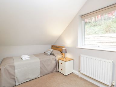 A bedroom with a single bed a nightstand with a lamp and a window at The Brambles in Monmouth